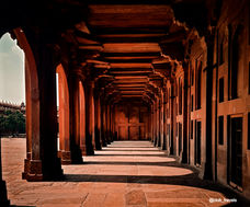 Long corridor with arched entrance and detailed stonework, bright sunlight in India