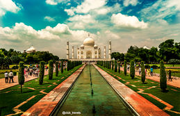 Taj Mahal, India, seen from a long water channel with trees around; car rental in India