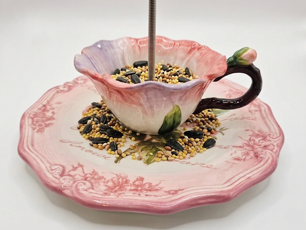 Thumbnail: Close-up of a decorative rose-patterned teacup bird feeder filled with mixed wild bird seed