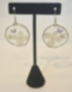 A pair of lightweight, handmade resin earrings featuring white flowers and a delicate butterfly accent