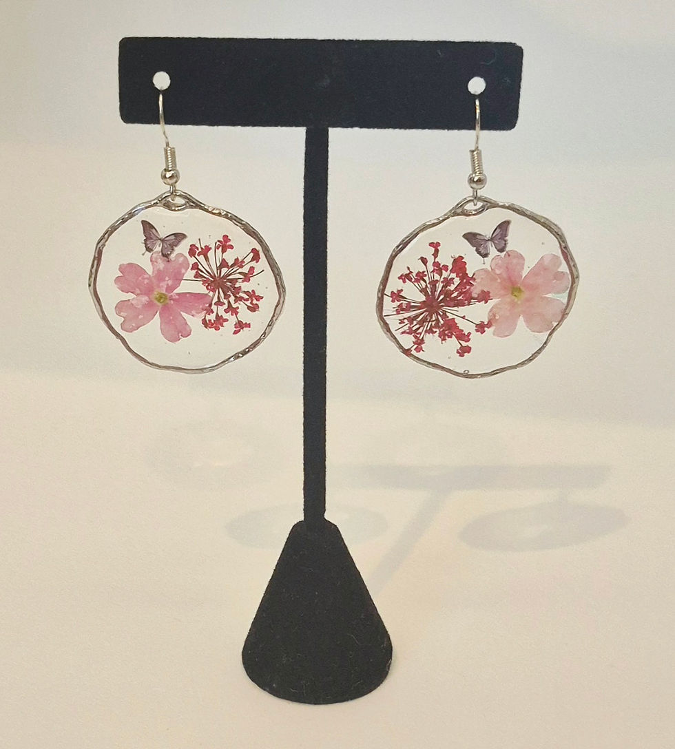 A pair of lightweight, handmade resin earrings featuring pressed pink flowers and a delicate butterfly accent