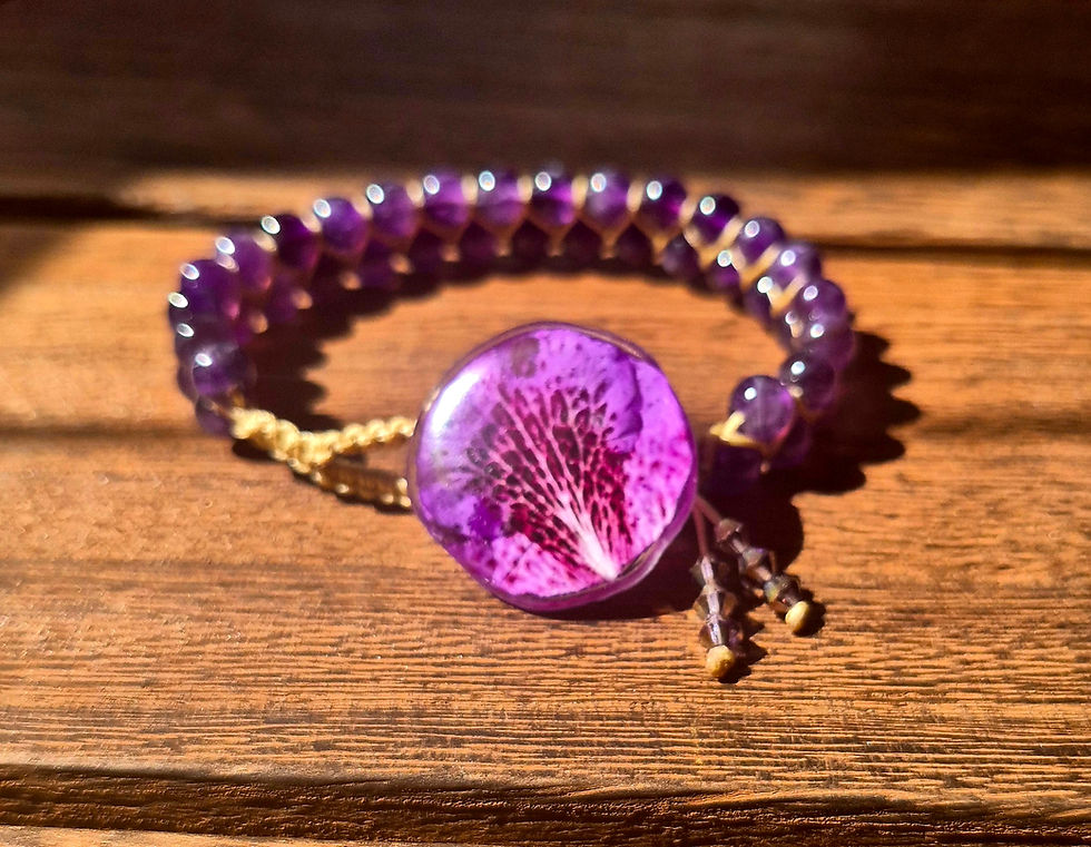 A full, elegant view of the handmade amethyst bracelet, highlighted by the striking rhododendron petal button