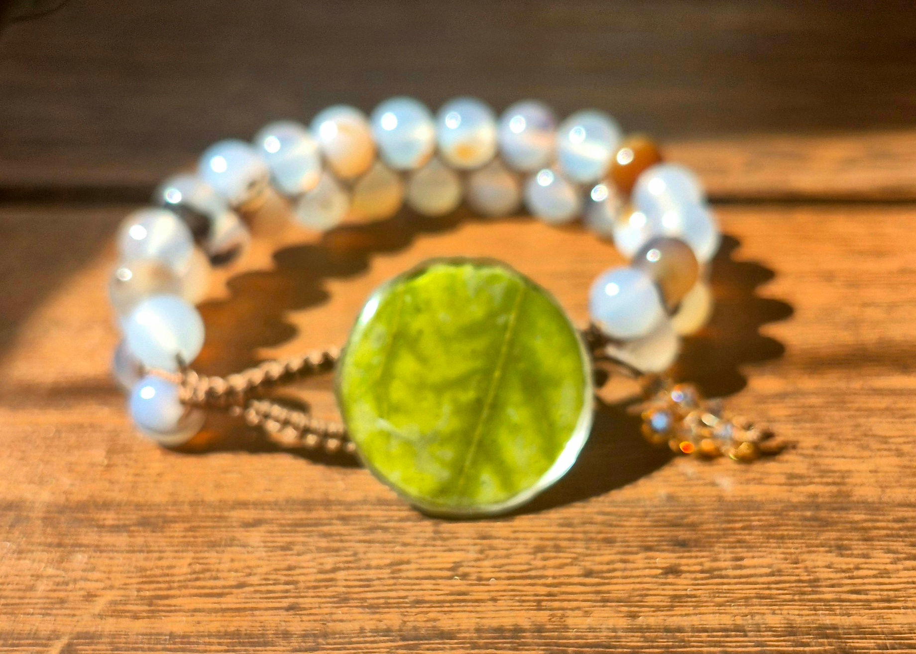 A full, elegant view of the handmade white agate bracelet, highlighted by the striking maple leaf button