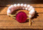 A full view of a handmade lavender beaded bracelet featuring a vibrant, preserved rose petal button clasp