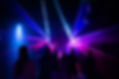 Crowd in a laser-lit rave environment, colourful lights slicing through mist as people dance in rhythm.
