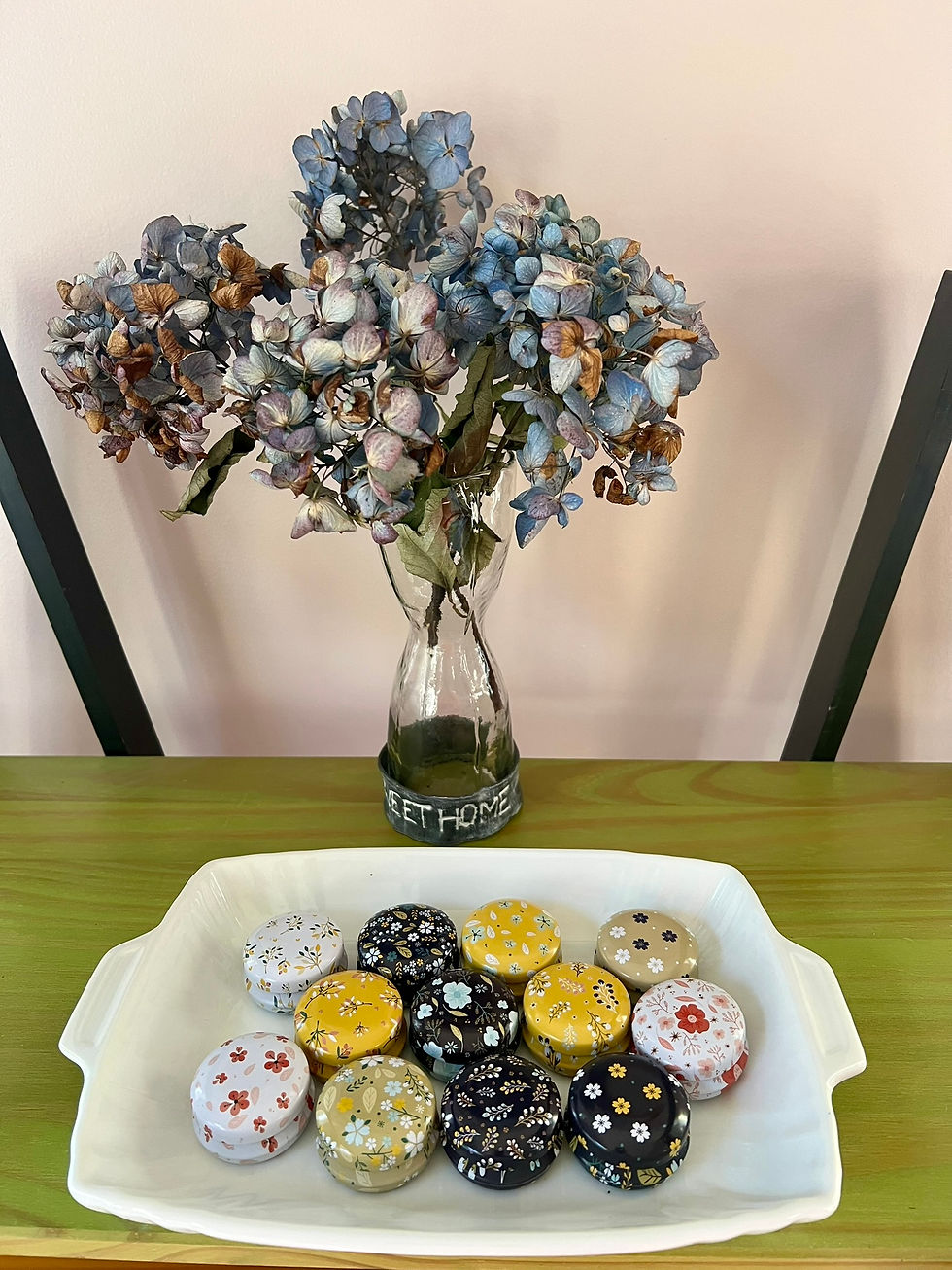 Vintage charm meets floral elegance in the "Collection Fleur d'Âme." Dried hydrangeas in a rustic vase complement delicately designed floral tins, creating a serene and aesthetically pleasing display.