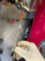 Gloved hand holding an oil dipstick.