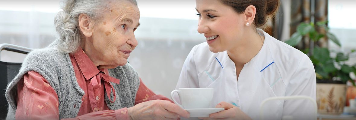 A nurse smiling at and providing compassionate care for an elder patient