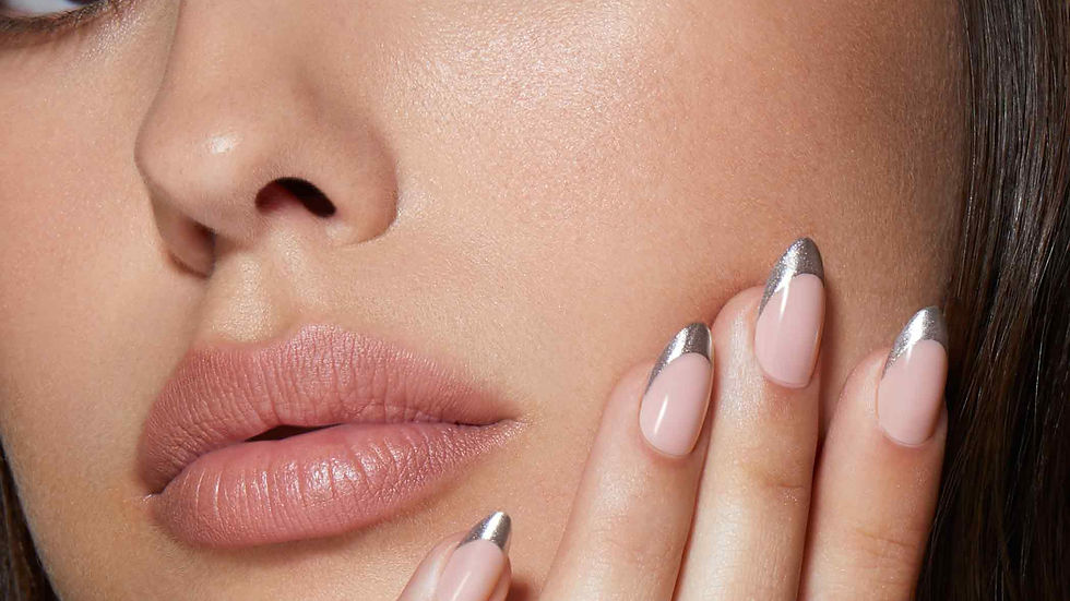 Close-up of a woman's face with smoky eye makeup, natural lips, resting her hand on her cheek. Fingernails have metallic silver tips.