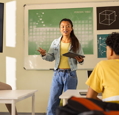 Presenting project in high school, teenage girl holding tablet with classmates watching. E