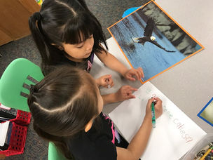 Two children learning to write on a piece of paper