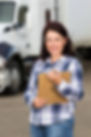 Caucasian woman smiling and holding a brown folder in front of a semi-truck