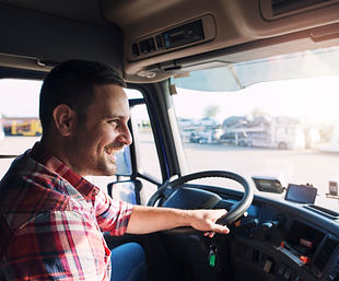 Caucasian truck driver smiling as he is driving his semi-truck