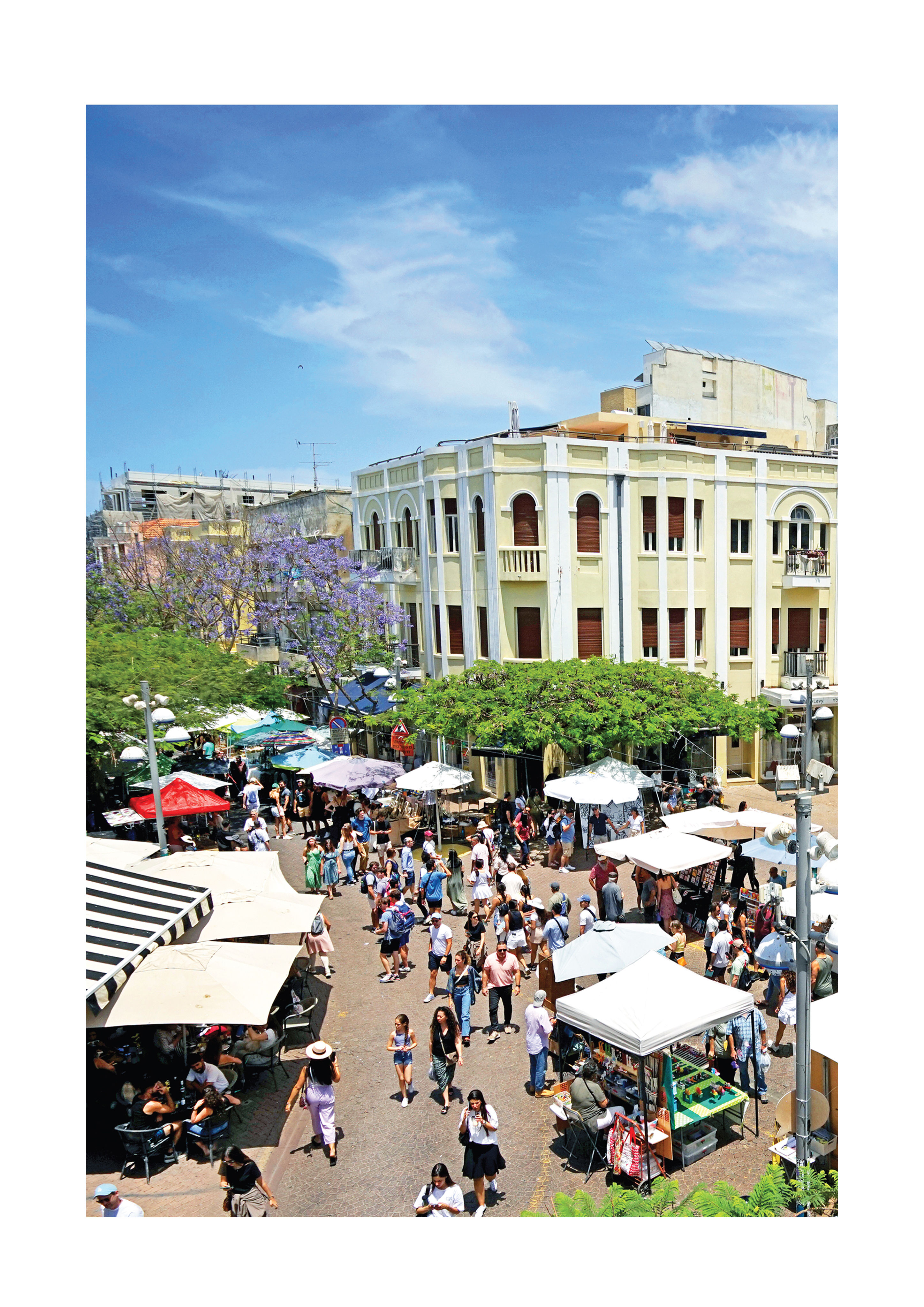 Nachlat Binyamin Art Fair in Tel Aviv with bustling market stalls, historic architecture, purple jacaranda trees, and visitor