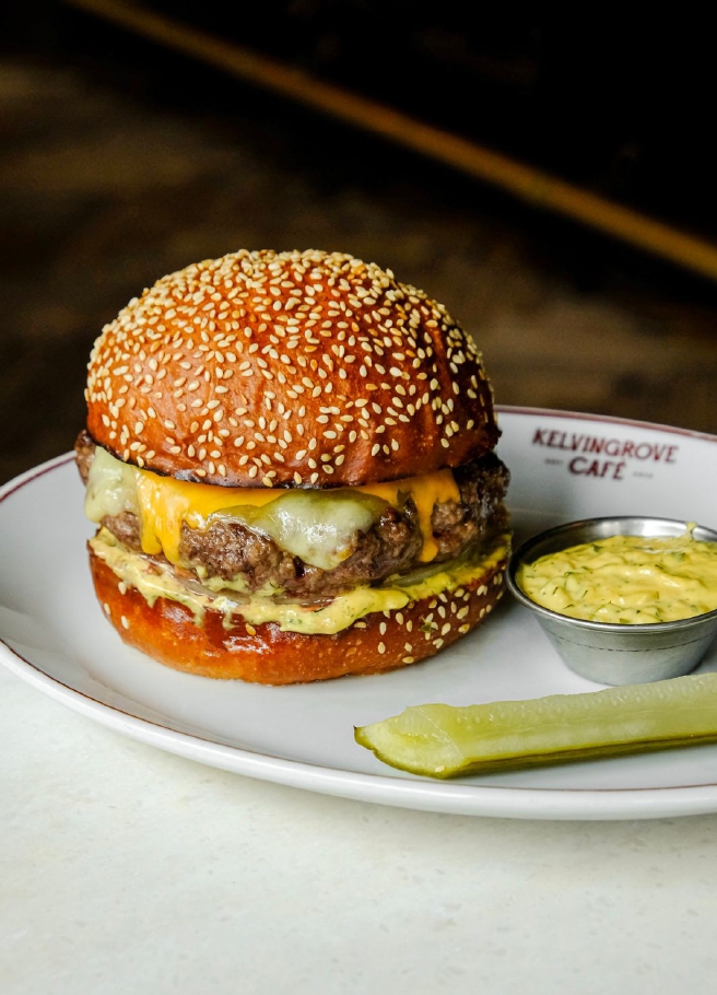Places to Eat Near Glasgow's Big Venues: Scotstoun, Hampden, the Hydro and More 8 A cheeseburger with a pickle and a pot of sauce on a Kelvingrove Café plate