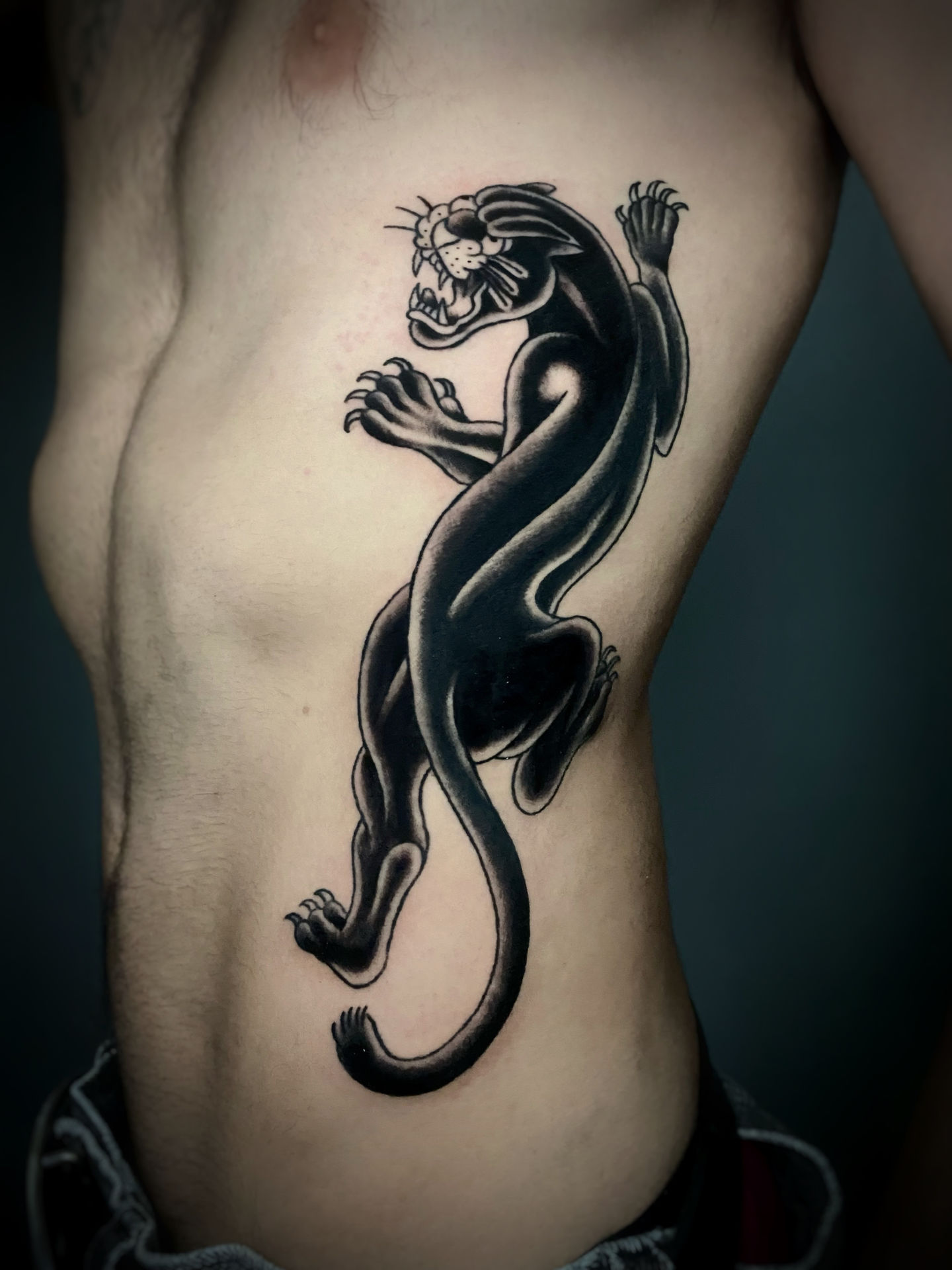 traditional american tattoo of black crawling panther on ribs