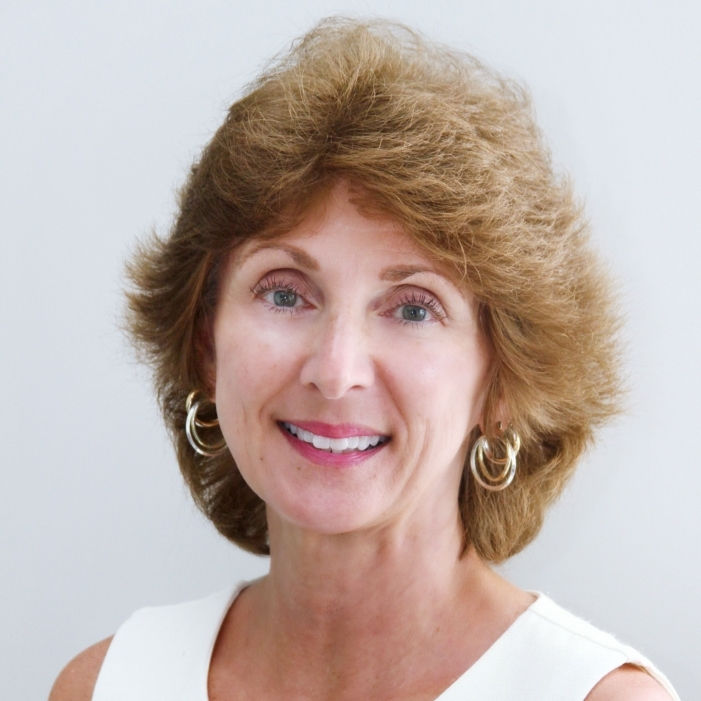 Portrait of a smiling woman with wavy brown hair.