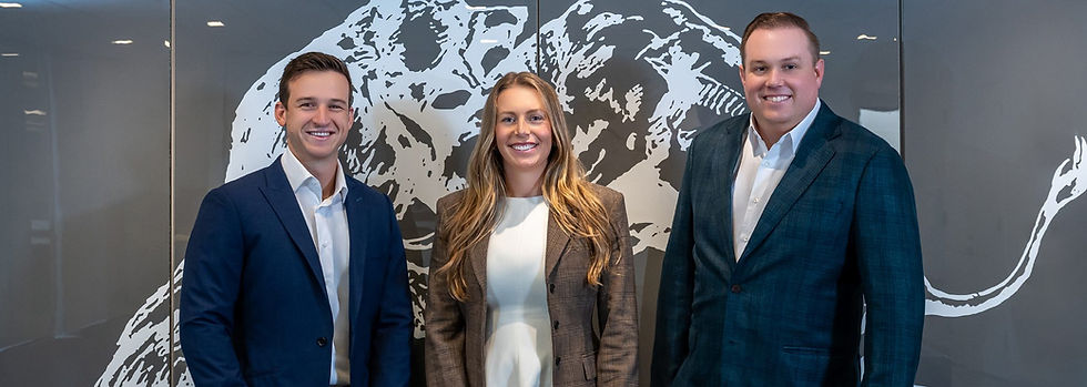 Three smiling professionals standing in front of a mural.