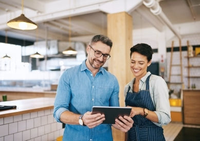 Two colleagues reviewing data on a tablet in a cafe