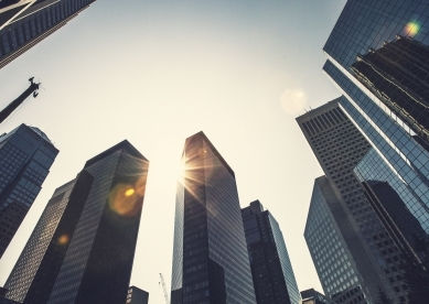 Low angle view of city skyscrapers against a bright sky.