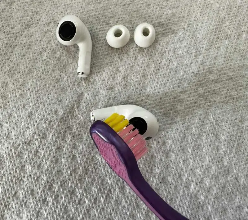 Cleaning AirPods with a brush
