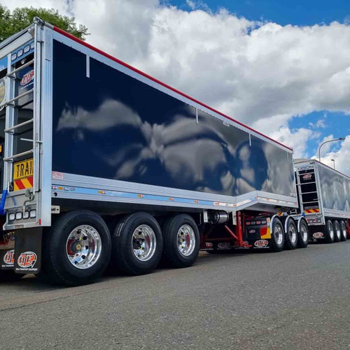 Road train with two blue trailers reflecting clouds