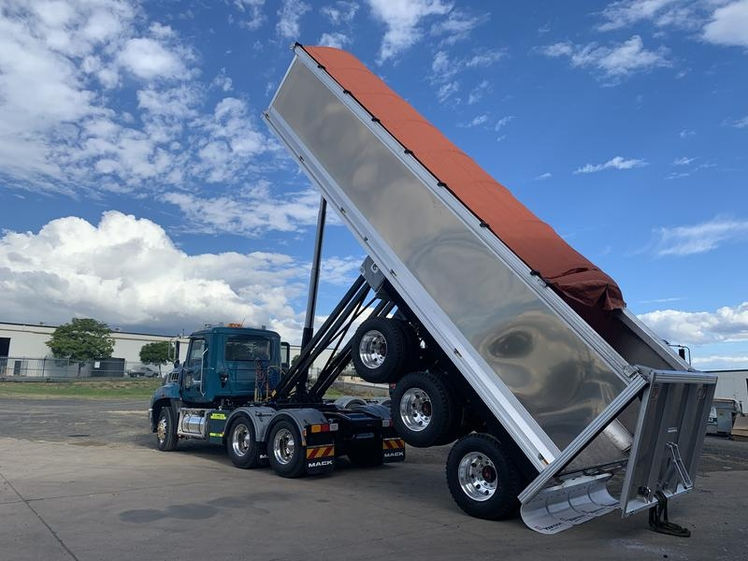 Blue dump truck with raised silver trailer and red cover