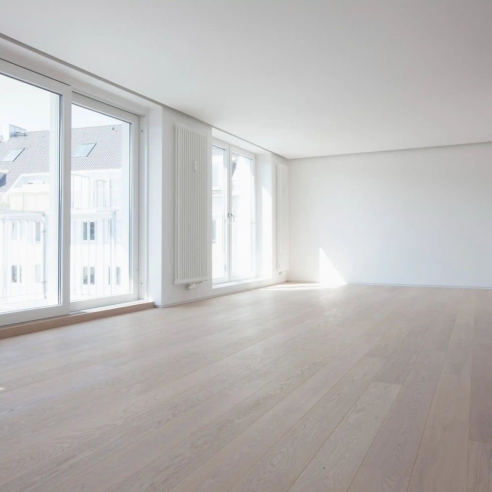 Example of acoustic ceiling removal after. Empty room with light wood floors, white walls, and large windows showing city buildings. Bright natural light creates a clean, airy feel.