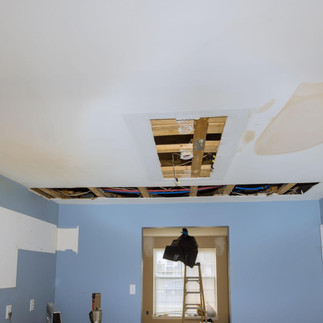 Drywall cut open for plumbing repair with exposed pipes and wall openings