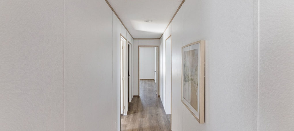 Long white hallway with wood floor and framed art