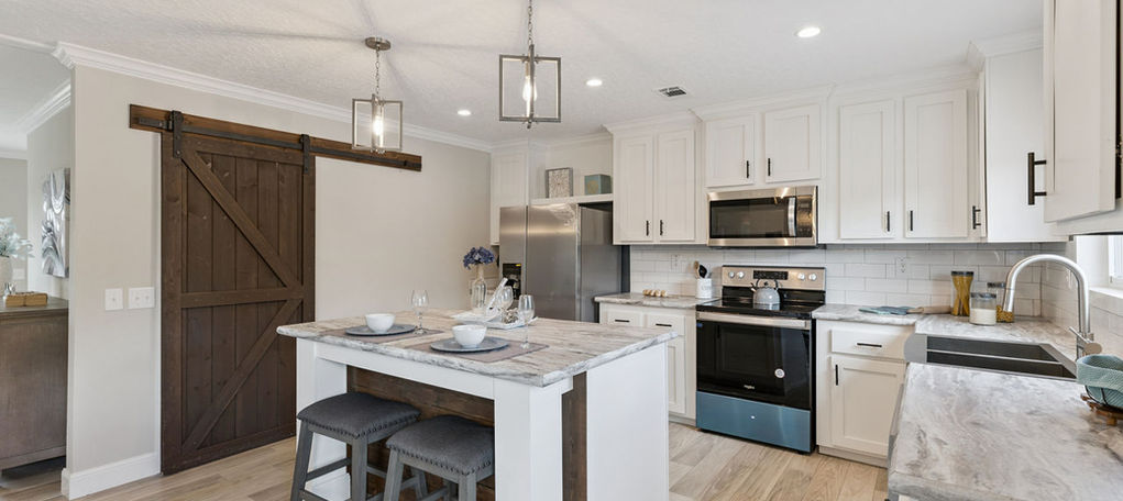 Modern kitchen with white cabinets and dark barn door.