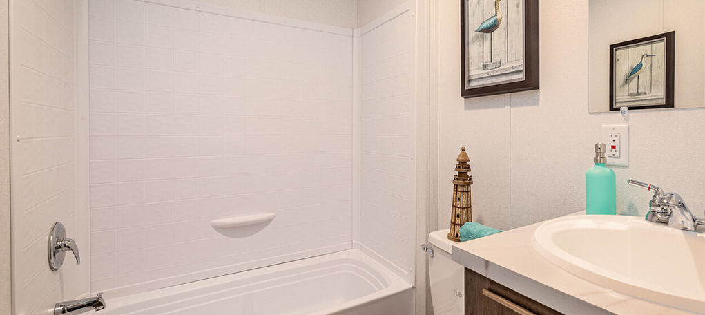 Bathroom with white bathtub, toilet, and vanity with sink