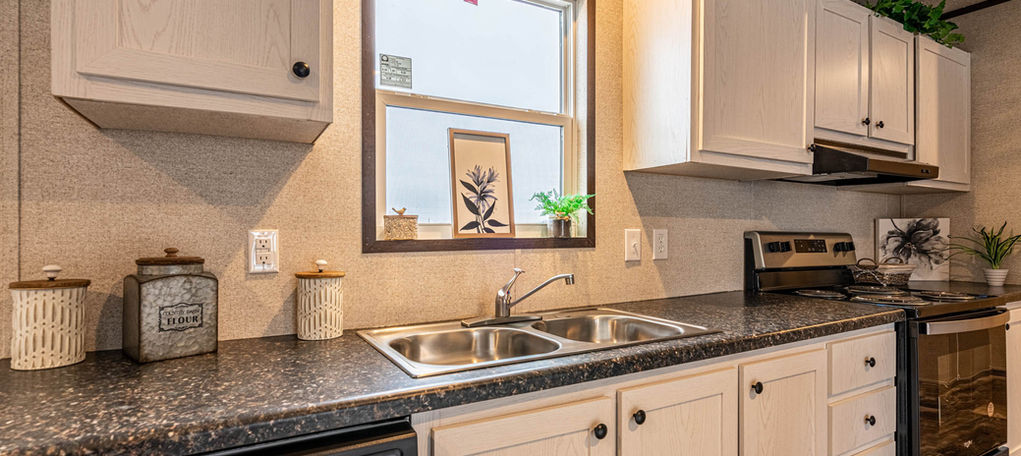 Kitchen with white cabinets, dark counters, and stainless sink