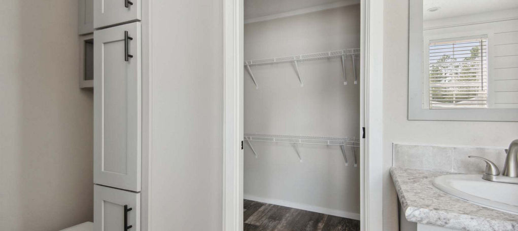 Modern bathroom with white cabinets and walk-in closet.