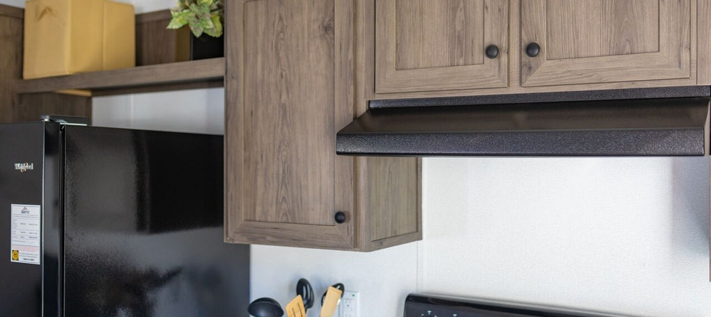Modern kitchen with wooden cabinets and black appliances.
