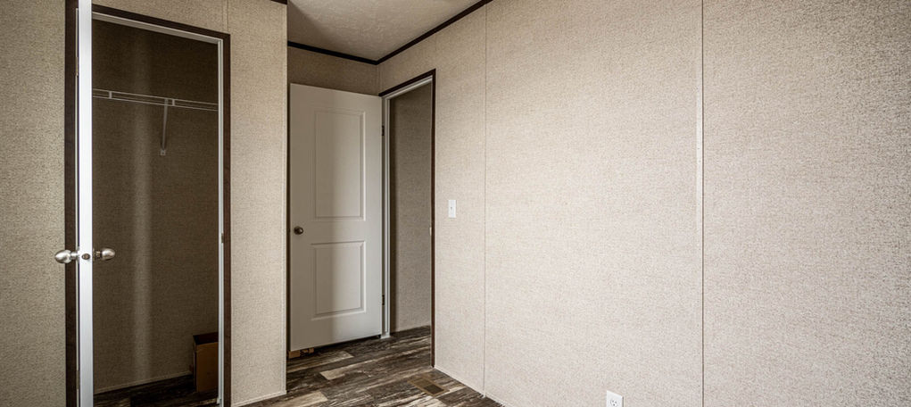 Empty bedroom with open closet and wood-look floor.
