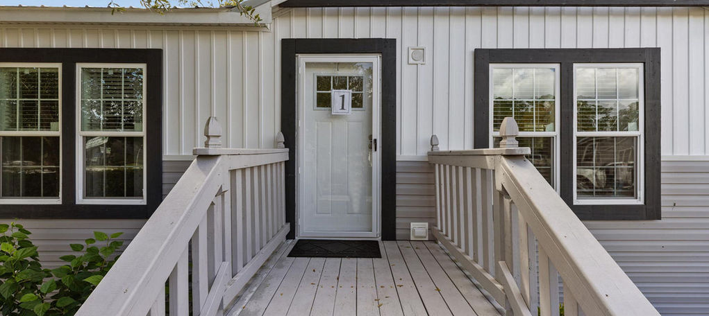 Modern white cottage entrance with wooden ramp