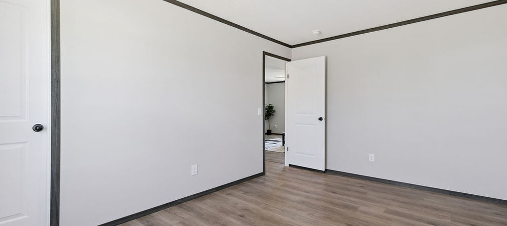 Empty room with gray walls, wood floor, and two doorways