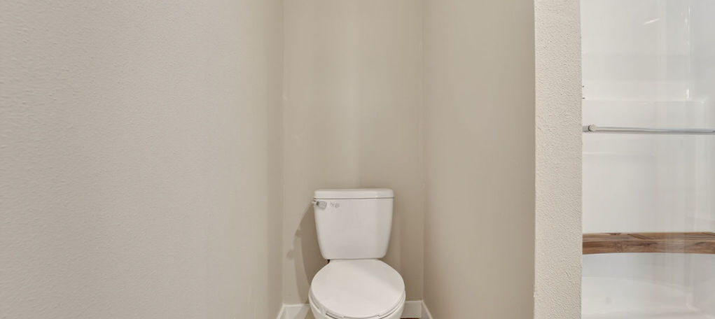 White toilet in a bathroom nook next to a glass shower.