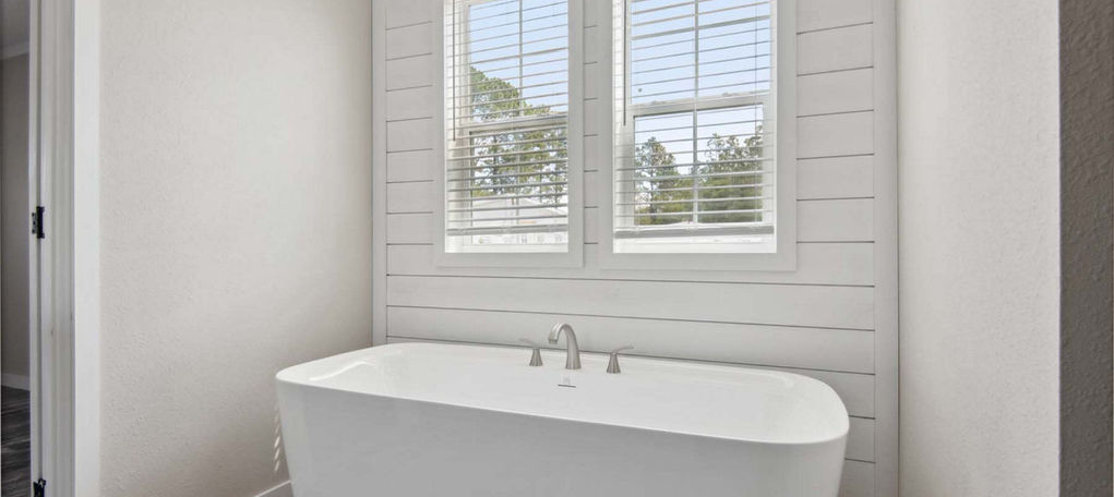Modern freestanding bathtub below windows with shiplap wall