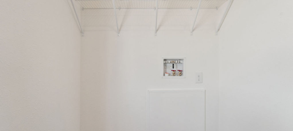 White wire shelf in a laundry room hookup area.