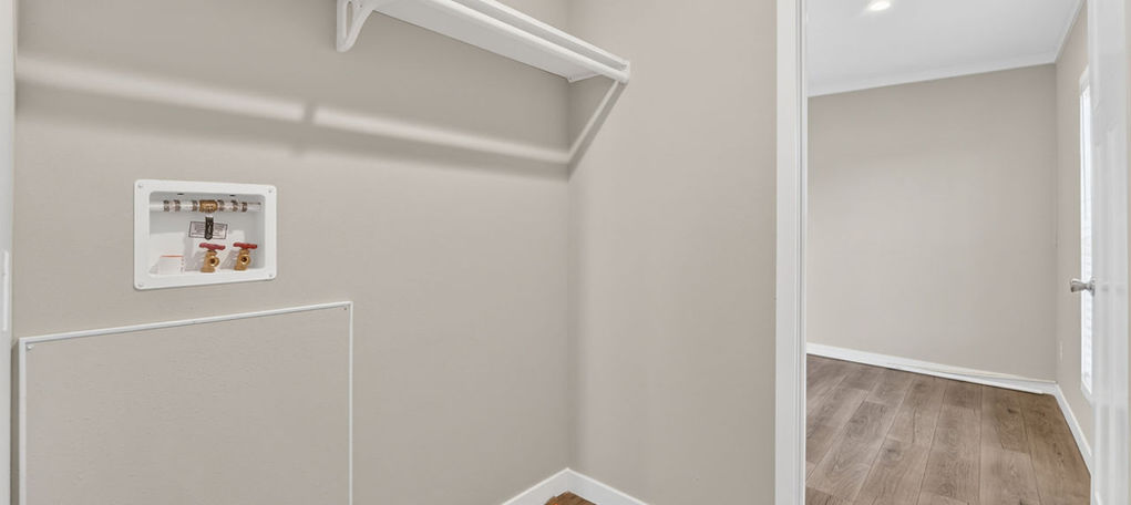 Laundry closet with white shelving and wood flooring