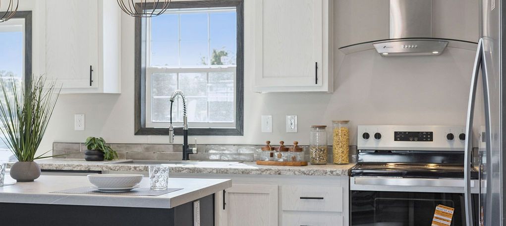 Modern kitchen with white cabinets, dark island, and stainless steel appliances