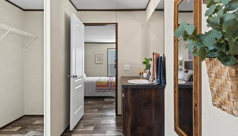 Hallway with closet, bedroom, and vanity with mirror