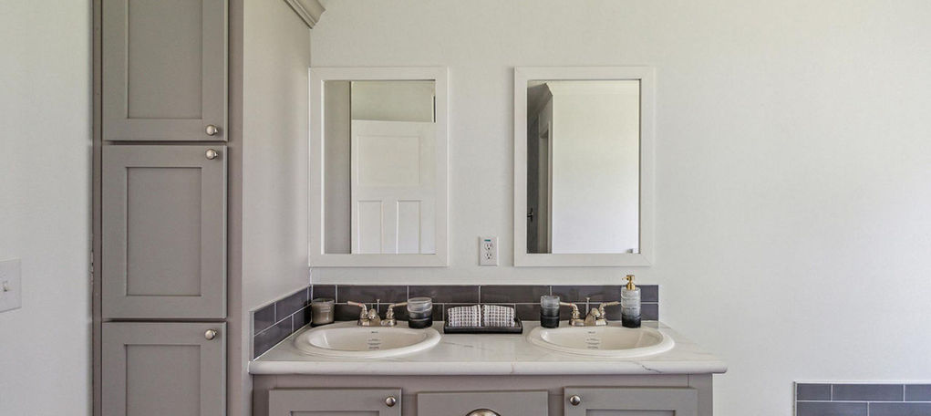 Modern grey double vanity with white sinks and mirrors.