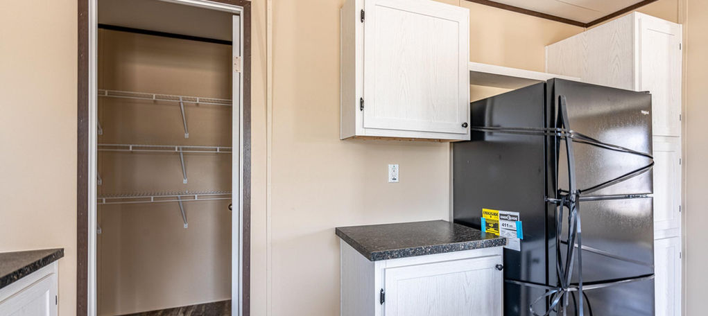 Modern kitchen with white cabinets, black fridge, and pantry.
