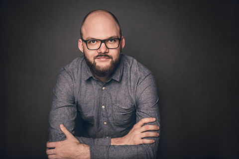 Dynamische Portraitaufnahme, ein Mann stützt sich auf einen Tisch