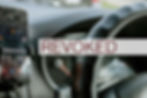 Close-up of a car dashboard with a smartphone on a mount and the word "REVOKED" overlaid