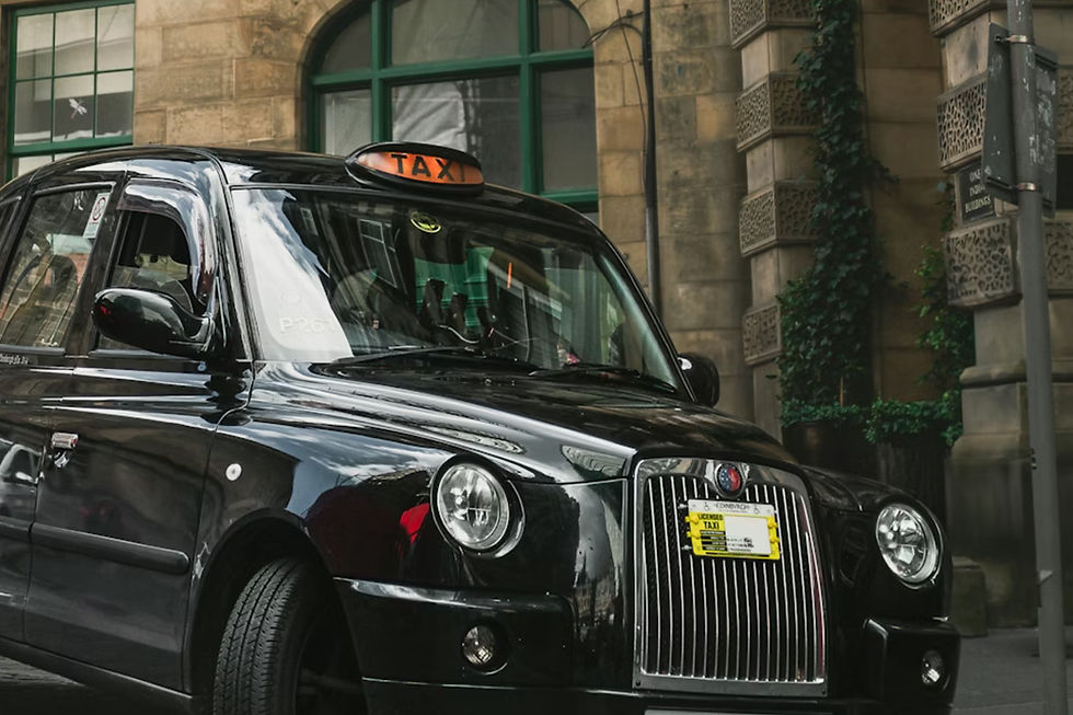 Black taxi with "TAXI" sign on a city street, parked near a building with green-framed windows and ivy-covered walls. License visible.