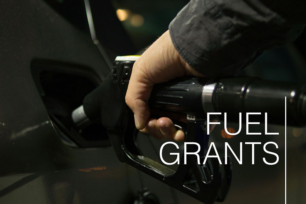 Hand pumping gas into a car at night, with the text "Fuel Grants" overlaid in white. The scene is dimly lit with a focus on the nozzle.